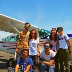 Group posing in front of airplane