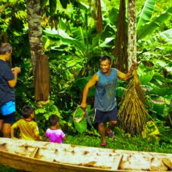 Indigenous man and children next to boat in the jungle